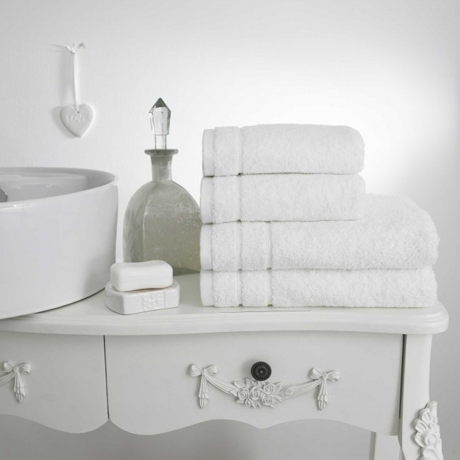 4 fluffy luxury white towels folded and piled on top of a white painted dressing table